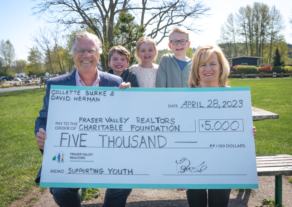 A couple and their three grandchildren are holding a large commemorative cheque for $5,000 made out to the Fraser Valley Realtors Charitable Foundation.