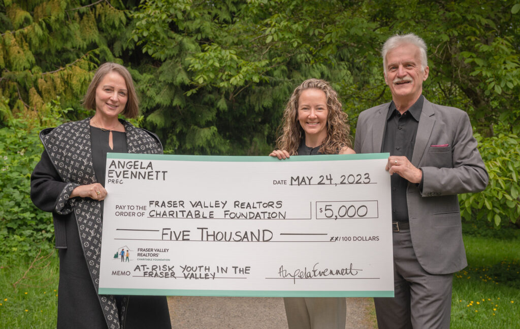 A Realtor and two representatives from the Foundation are holding a large commemorative cheque for $5,000 made out to the Fraser Valley Realtors Charitable Foundation.